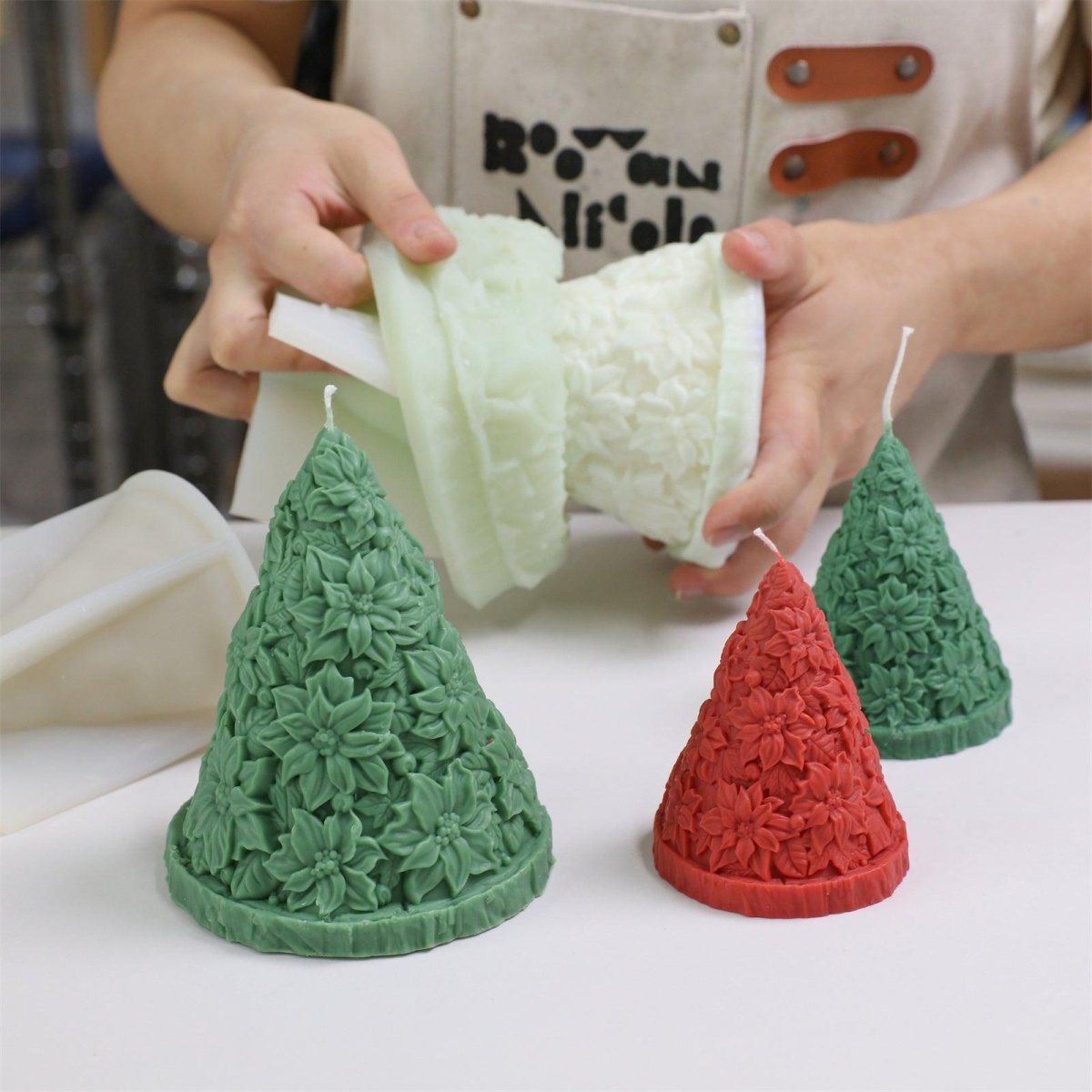 Unmolding poinsettia Christmas tree candles in red and green, showcasing detailed floral texture and DIY process - Boowan Nicole