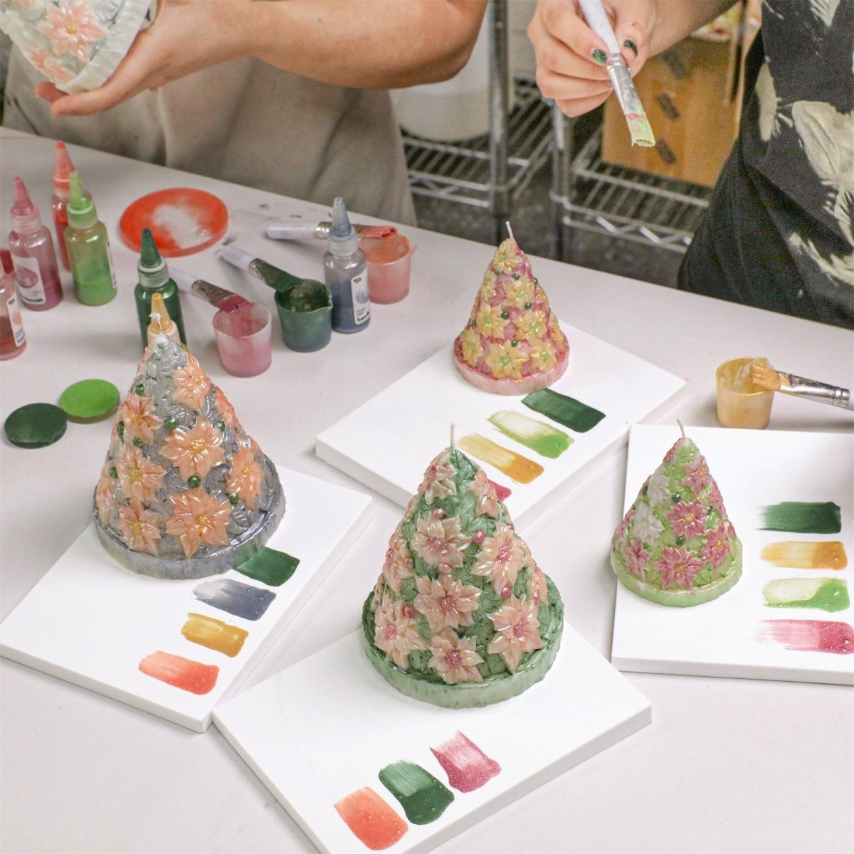 Hand-painted poinsettia Christmas tree candles in vibrant colors, displayed with matching pigment swatches and DIY tools - Boowan Nicole