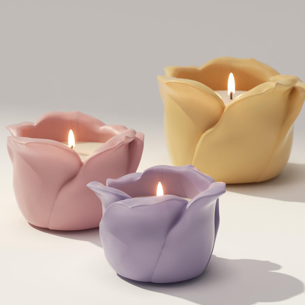 Three lit rose-shaped candle jars in pastel pink, purple, and yellow colors on a white background - Boowan Nicole