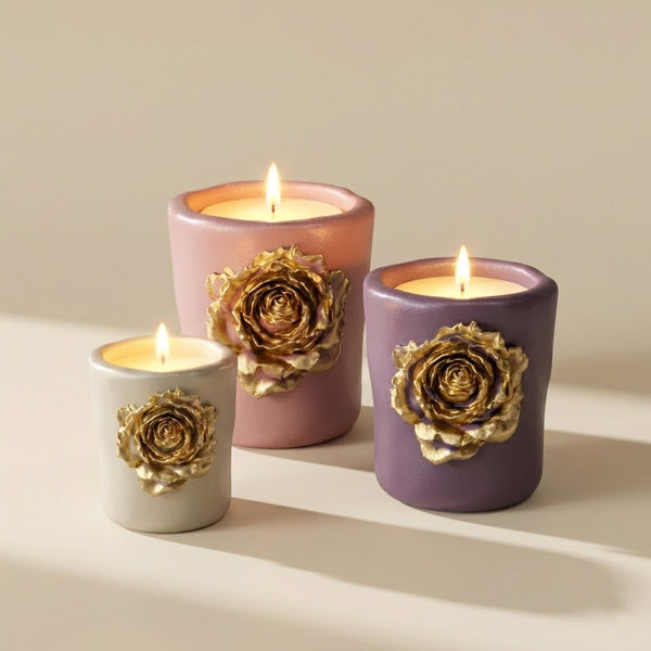Three lit candle jars with 3D golden rose relief in cream, pink, and purple casting warm light - Boowan Nicole