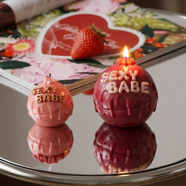 Pink and burgundy "SEXY BABE" candles with glitter letters and dripping wax on a mirrored surface - Boowan Nicole