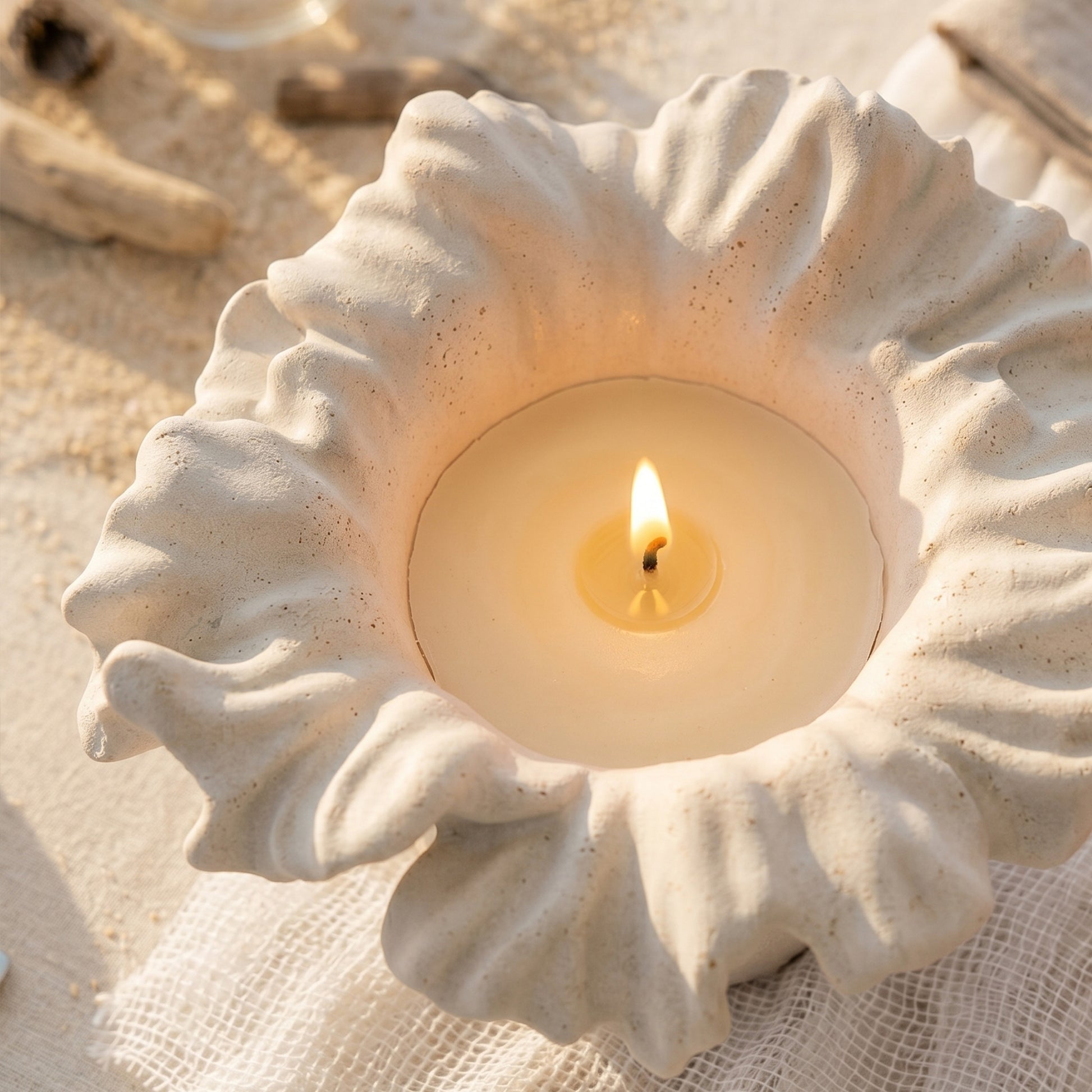 Close-up of lit Sea Anemone Bloom Candle Jar with speckled finish on beach linen - Boowan Nicole