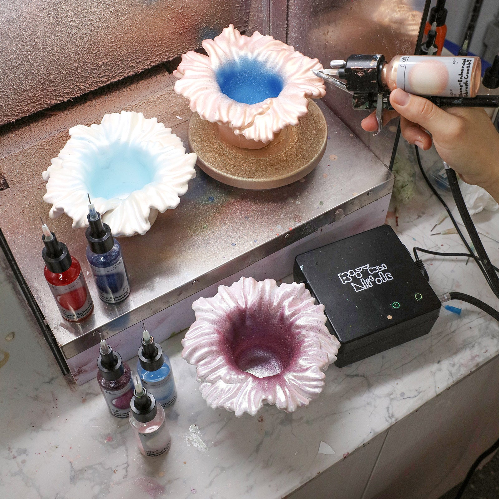 Airbrushing iridescent colors on Sea Anemone Bloom Candle Jar bases in workshop - Boowan Nicole