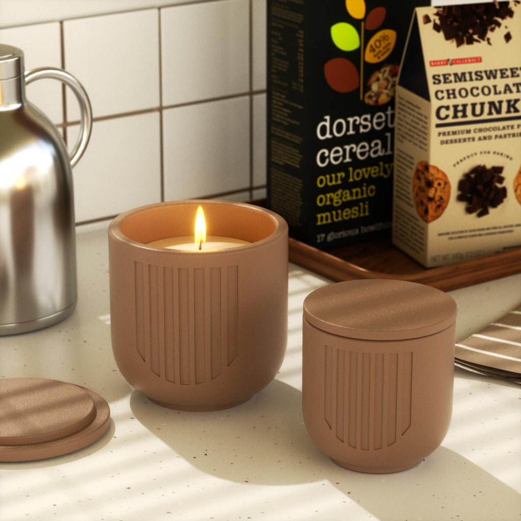 Lit brown candle jar and closed jar on kitchen counter with cereal boxes - Boowan Nicole