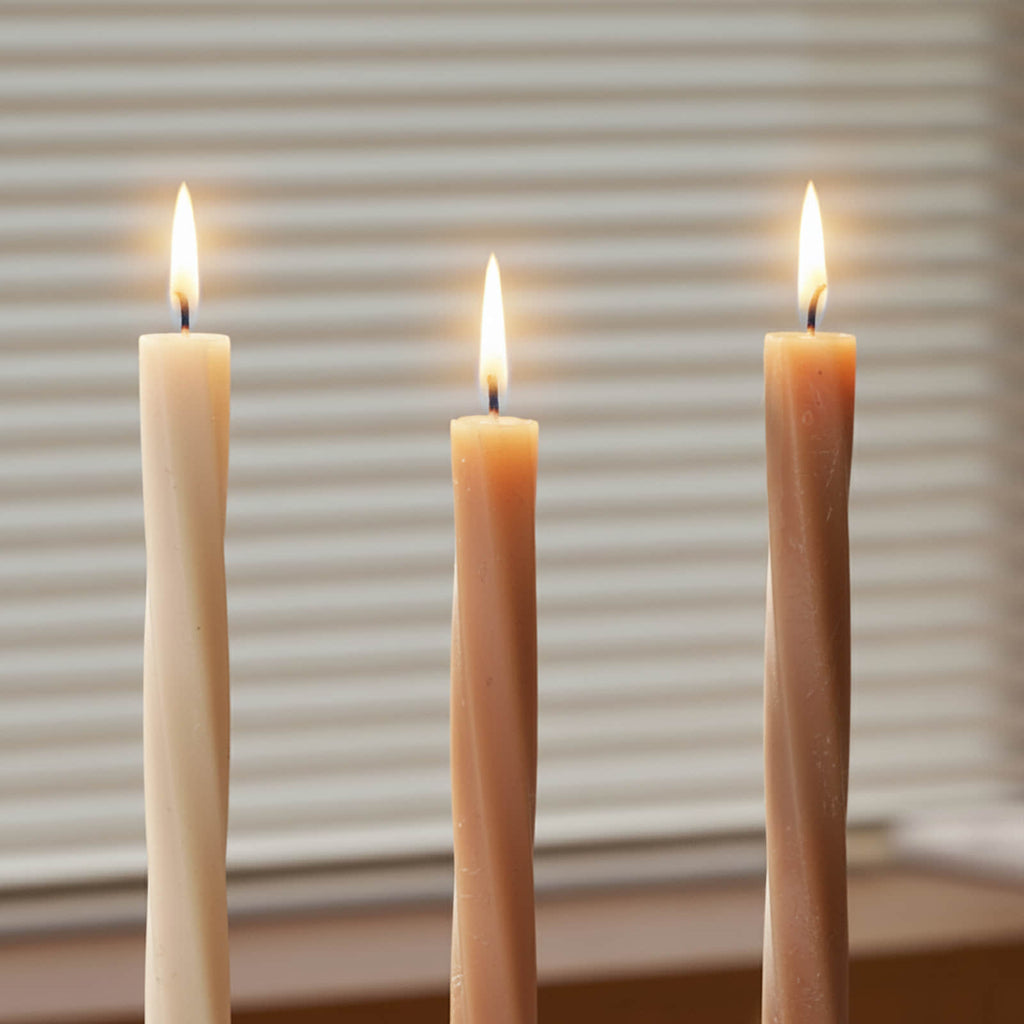 Close-up of three Serene Twist taper candles burning—cream, terracotta, and taupe—with subtle spiral detailing - Boowan Nicole