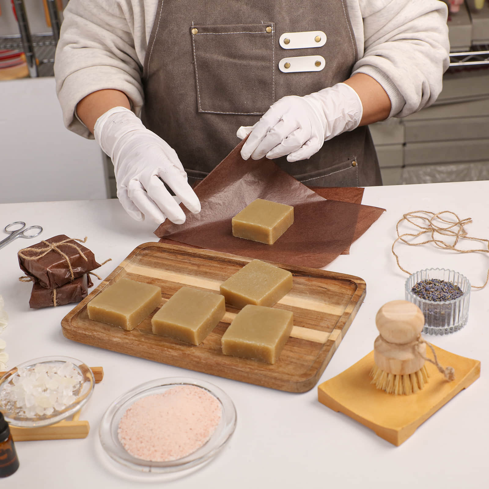 Artisan in a professional apron and gloves packaging handmade Herbal Sea Salt Soap bars for acne-prone skin - Boowan Nicole