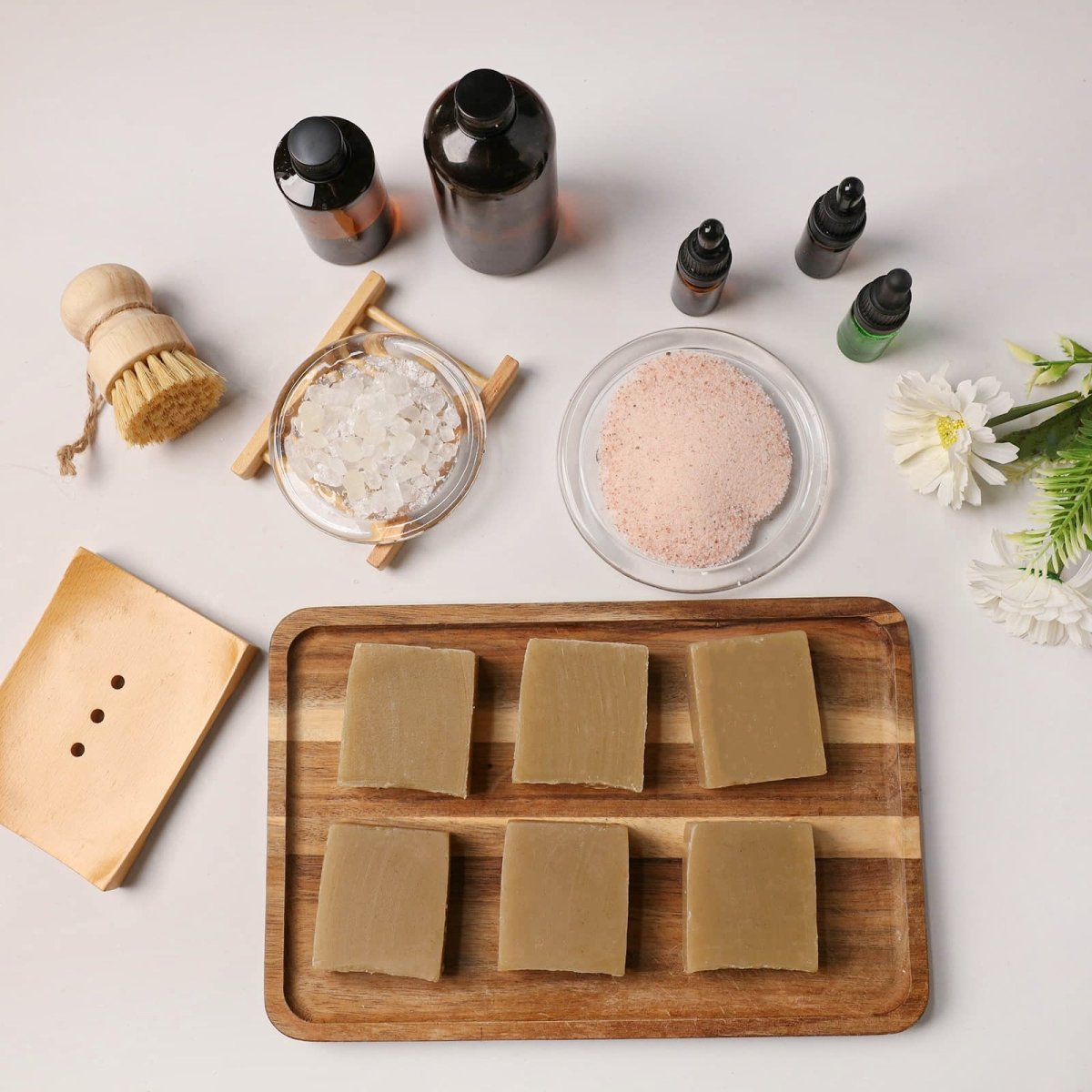 Natural herbal sea salt soap bars on a wooden tray, surrounded by pink Himalayan salt, essential oil bottles, and a wooden soap brush - Boowan Nicole