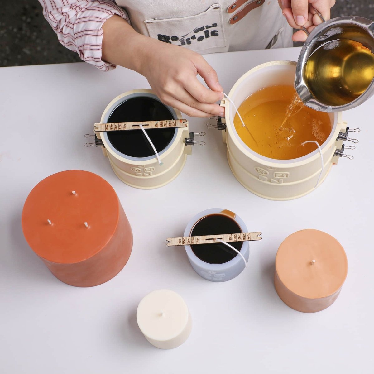 Top view—pouring melted wax into Simple Pillar Candle silicone molds with BN support shells and wick holders - Boowan Nicole