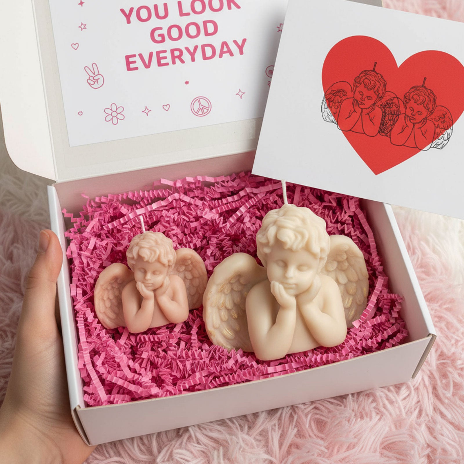 Gift box with small blush and large ivory winged cherub candles on pink crinkle paper - Boowan Nicole