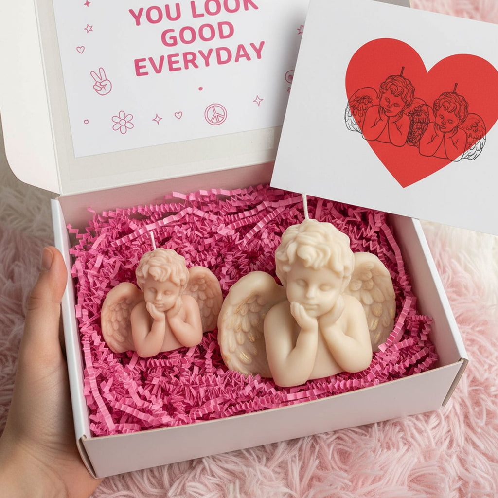 Gift box with small blush and large ivory winged cherub candles on pink crinkle paper - Boowan Nicole
