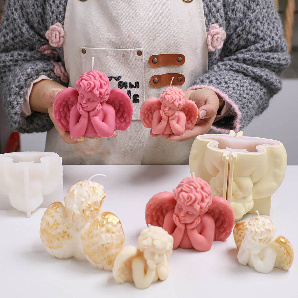 Maker holding large and small Sleeping Angel cherub candles; pink and ivory versions on table with support-shell silicone molds - Boowan Nicole