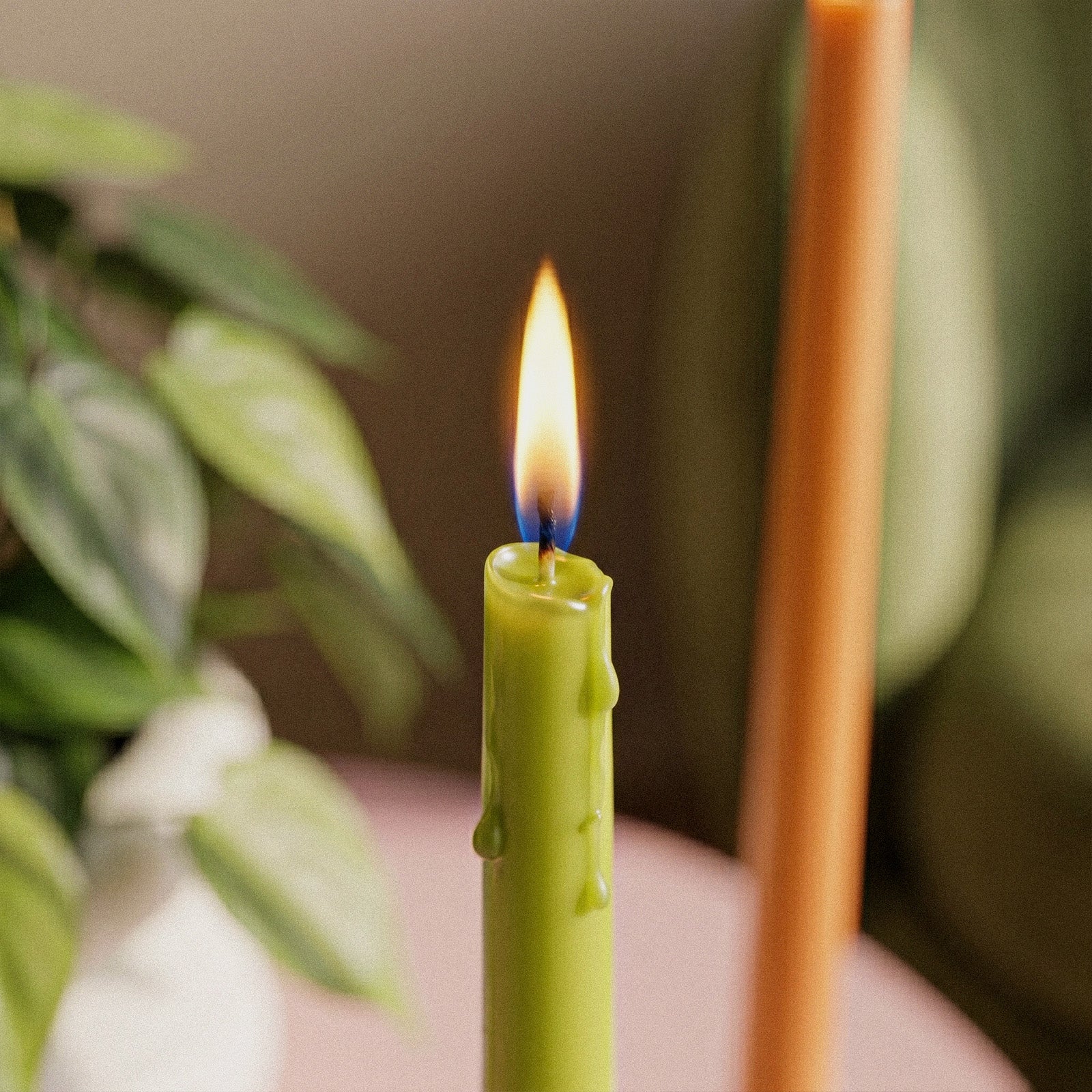 Ultra Slim Taper Acrylic Candle Mold, close-up of lit green slim taper candle with melted wax drips - Boowan Nicole