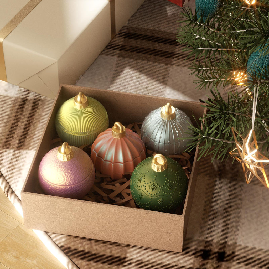 Gift box with five colorful Christmas bauble candle jars under a decorated tree - Boowan Nicole