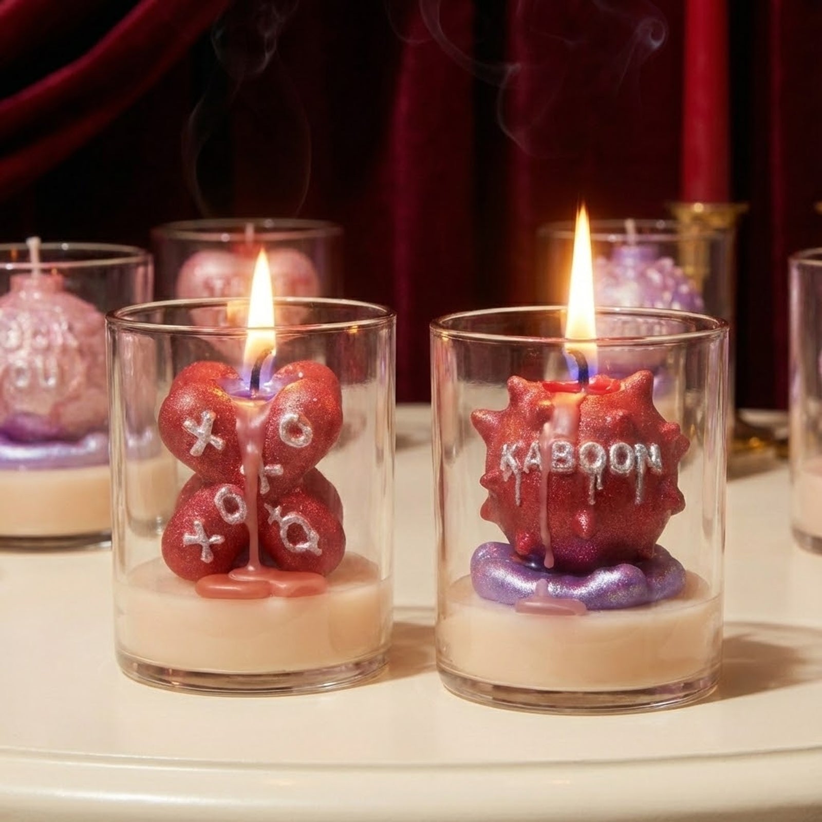 Close-up of lit Large Boomy Love 3D quote candles "XOXO" and "KABOOM" with silver glitter finish in clear glass jars - Boowan Nicole