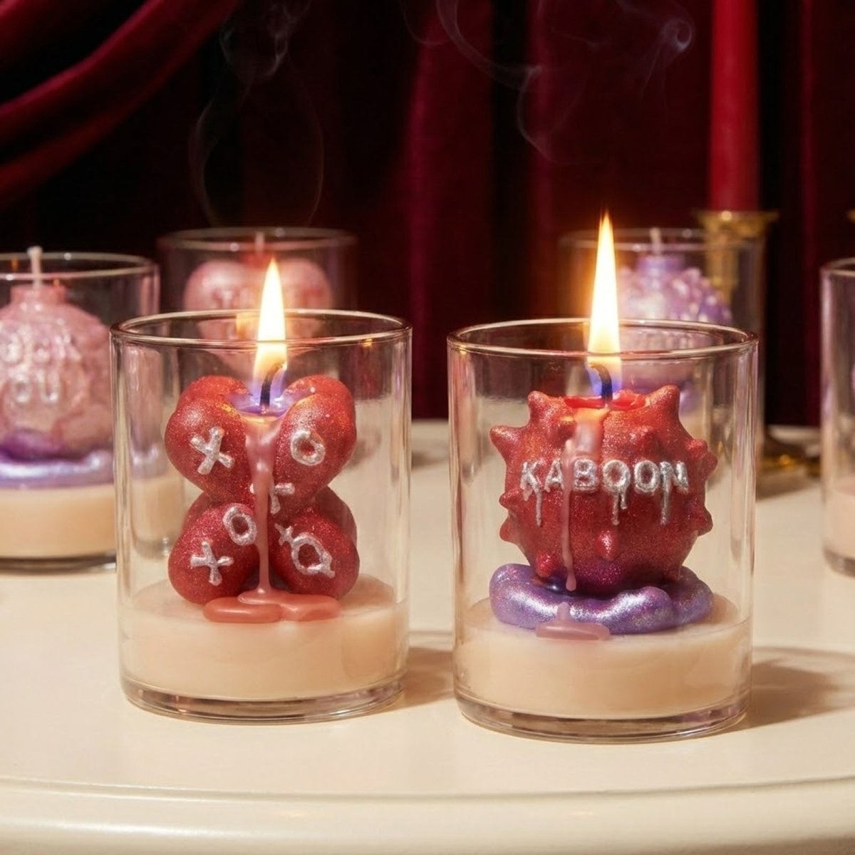 Close-up of lit Large Boomy Love 3D quote candles "XOXO" and "KABOOM" with silver glitter finish in clear glass jars - Boowan Nicole