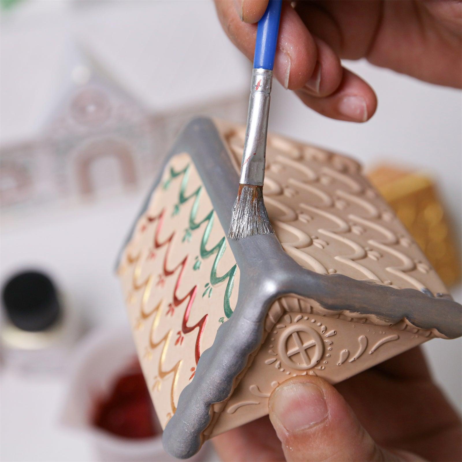 Hand painting silver mica powder on the roof of a gingerbread house candle jar - Boowan Nicole