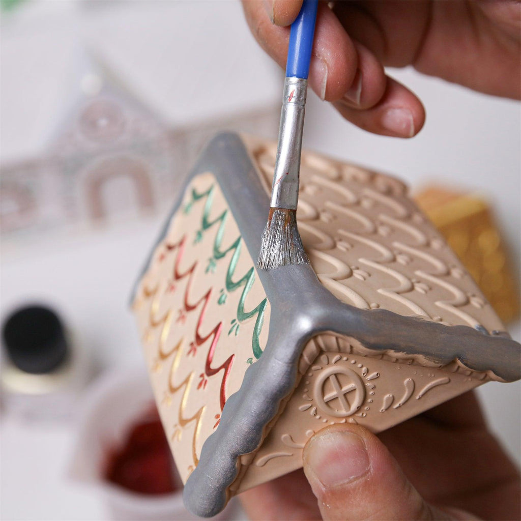 Hand painting silver mica powder on the roof of a gingerbread house candle jar - Boowan Nicole