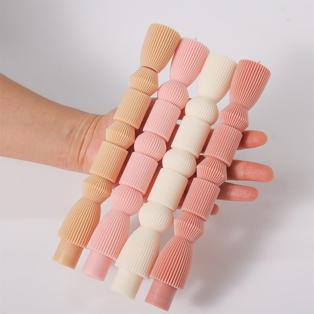 Holding and showcasing four different colors of taper candles -- Boowan Nicole