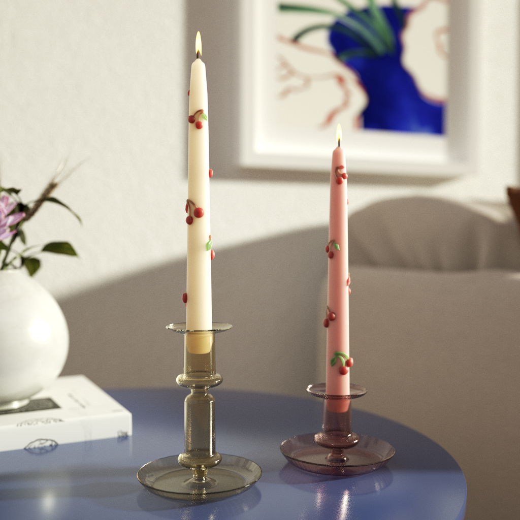 Two taper candles painted with cherry cameos burn slowly in crystal candlesticks, adding warmth to the ambiance