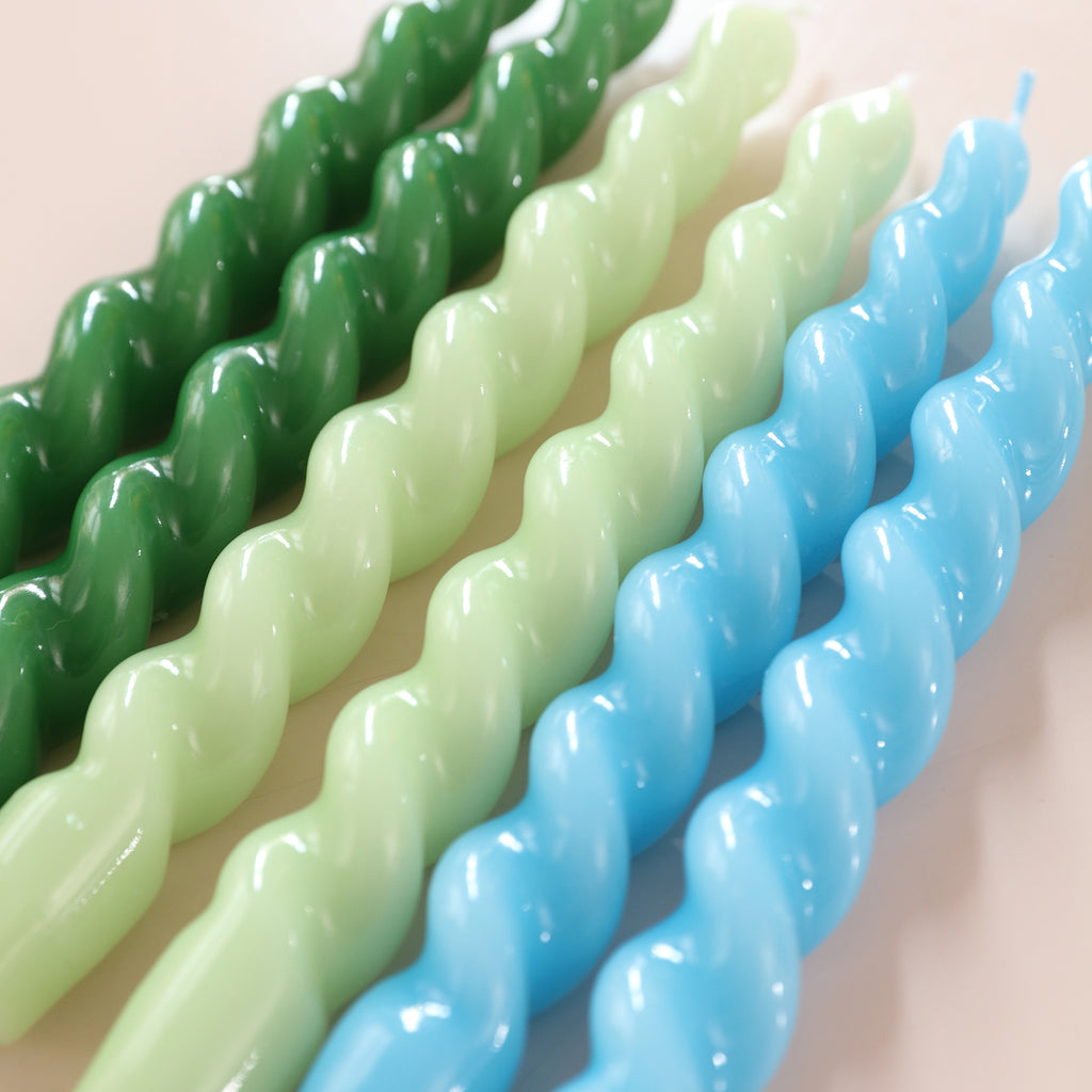 Close-up shot of six tapered spiral candles with smooth surfaces in blue, green and cyan colors - Boowan Nicole