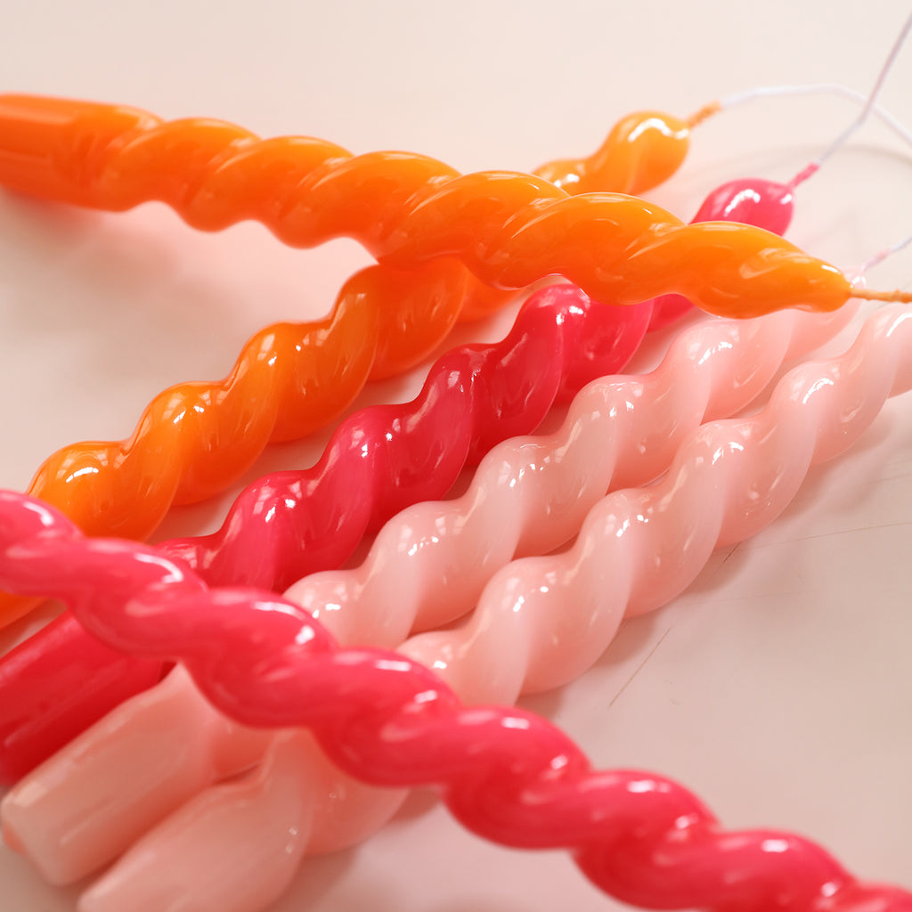 Six tapered spiral candles in orange, red and pink randomly placed on the table - Boowan Nicole