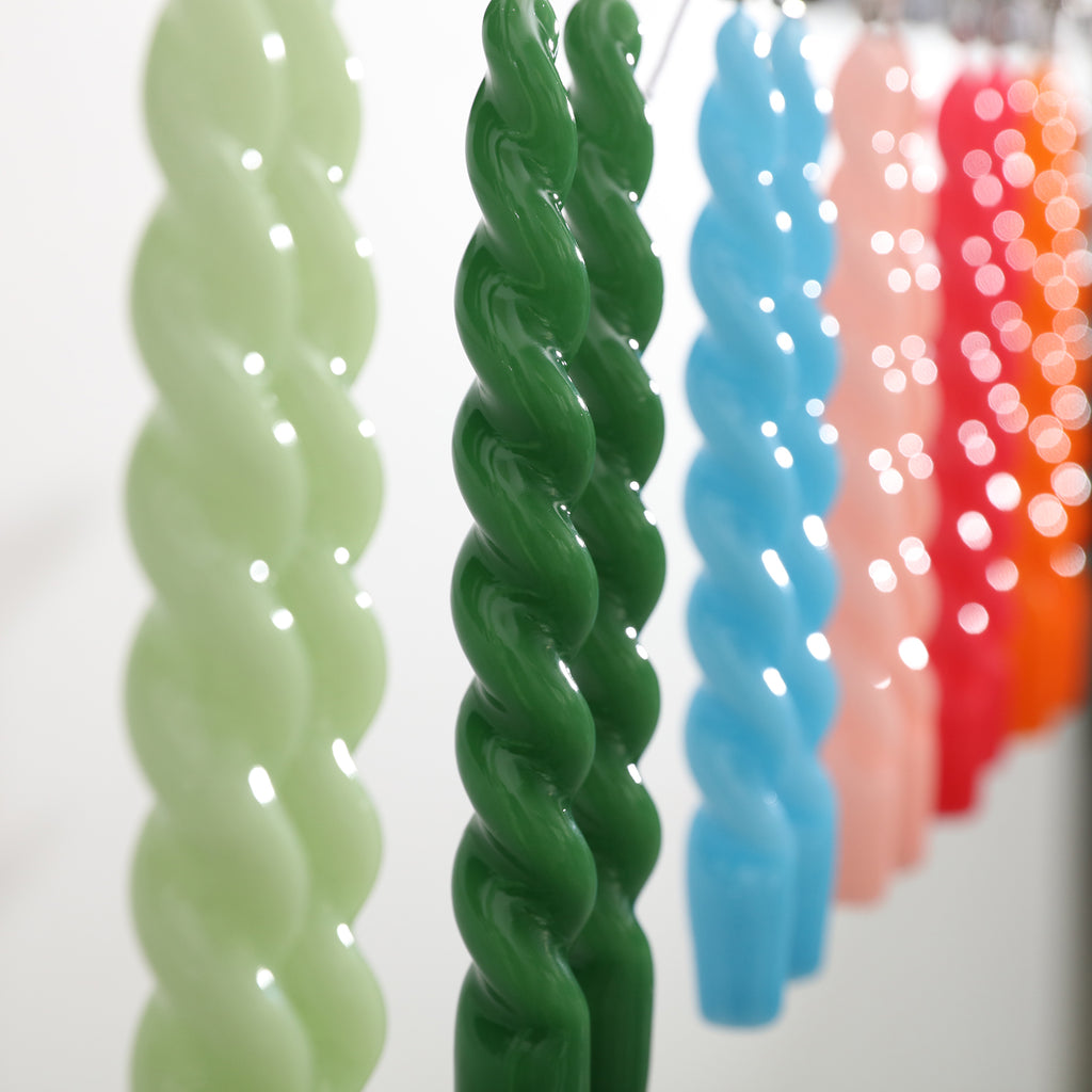 Smooth tapered spiral candles hanging on the shelf are placed randomly on the table - Boowan Nicole