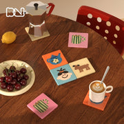 Colorful illustrated square drink coasters styled on a wooden coffee table with espresso, moka pot, cherries and a red chair - Boowan Nicole