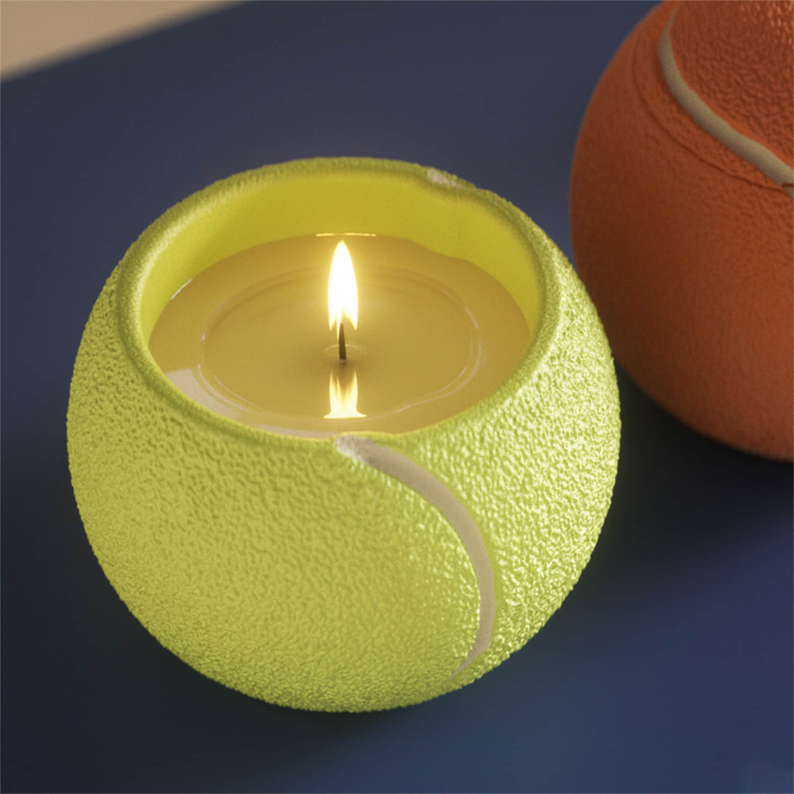 Lit candle in a neon-yellow tennis-ball candle jar, textured surface with white seam on a blue tabletop - Boowan Nicole