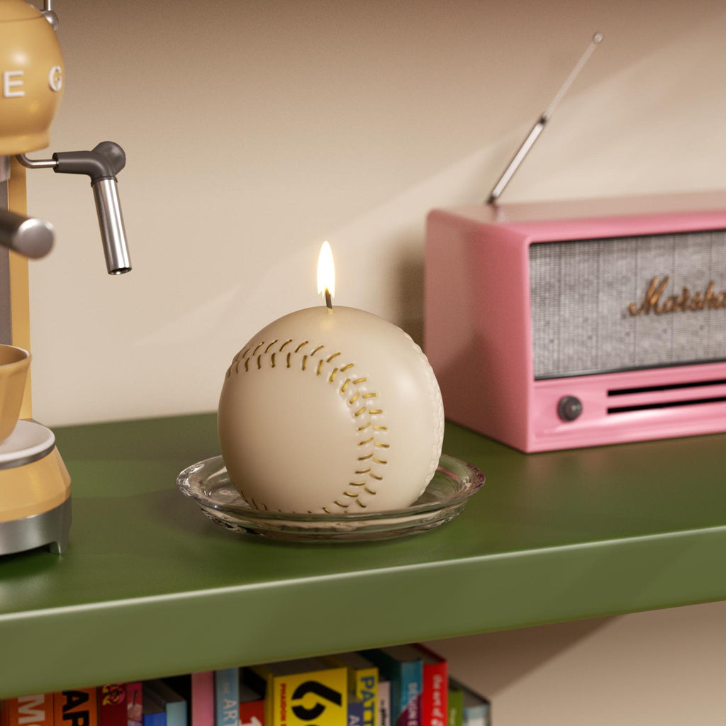 Baseball-shaped candle on a shelf with a pink radio and coffee machine in the background.