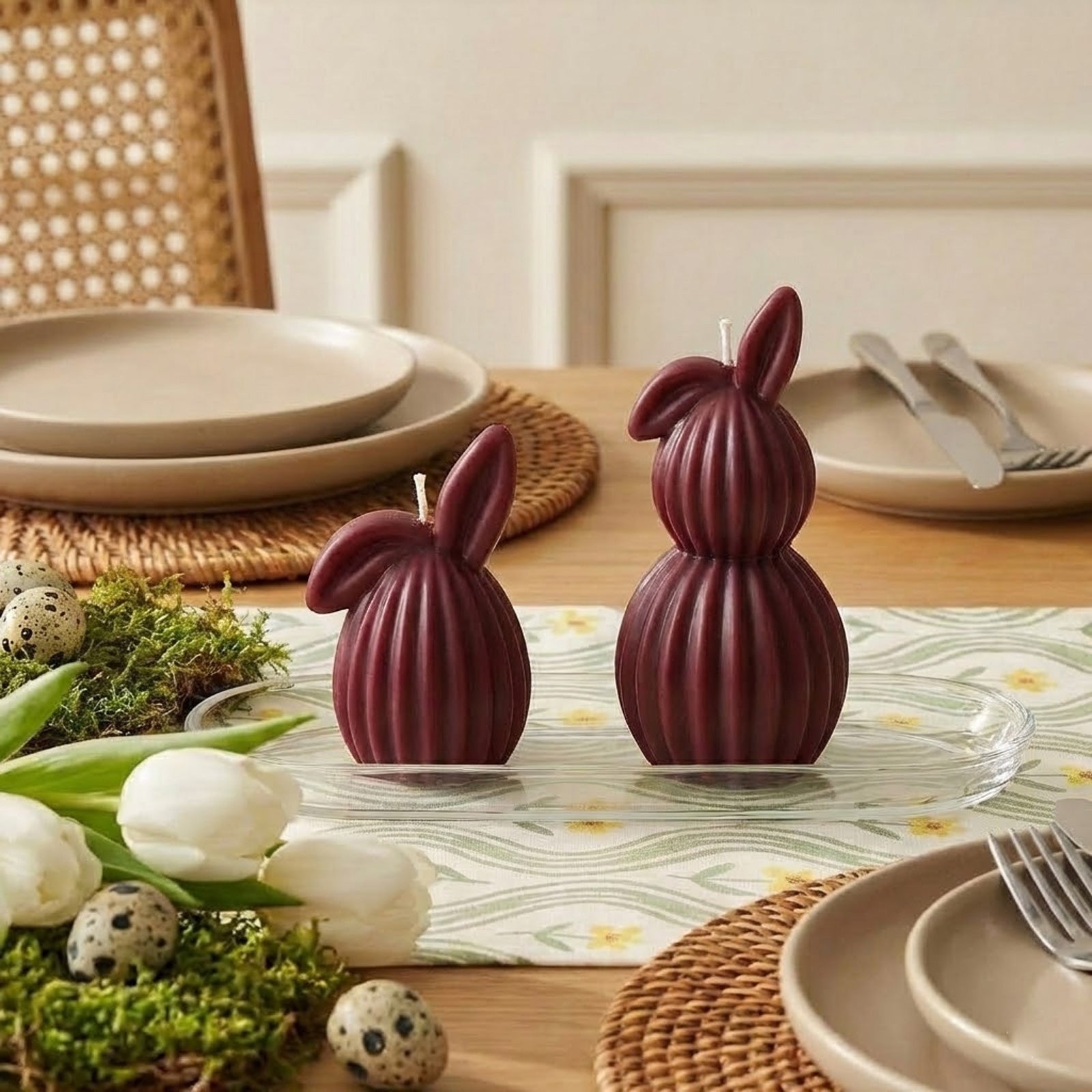 A stylish Easter tablescape featuring two burgundy ribbed bunny candles as the centerpiece, paired with neutral dinnerware and spring greenery. - Boowan Nicole