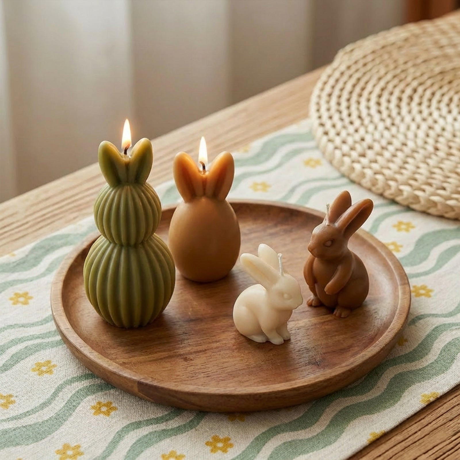A collection of lit bunny candles in olive, amber, cream, and brown, featuring realistic and ribbed rabbit designs on a wooden tray - Boowan Nicole