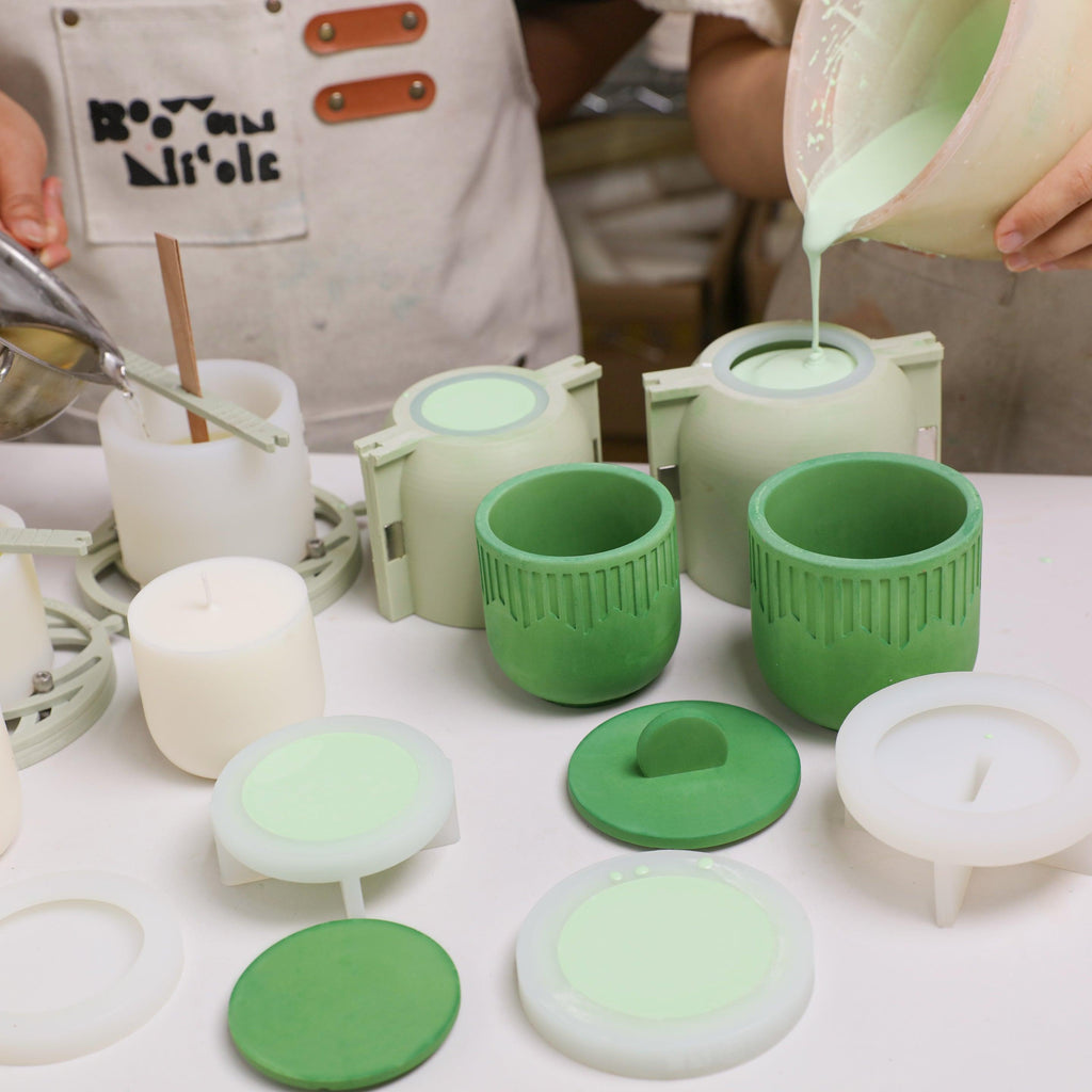 Pouring mixed concrete pigment and melted wax into silicone molds for candle jars and refills - Boowan Nicole