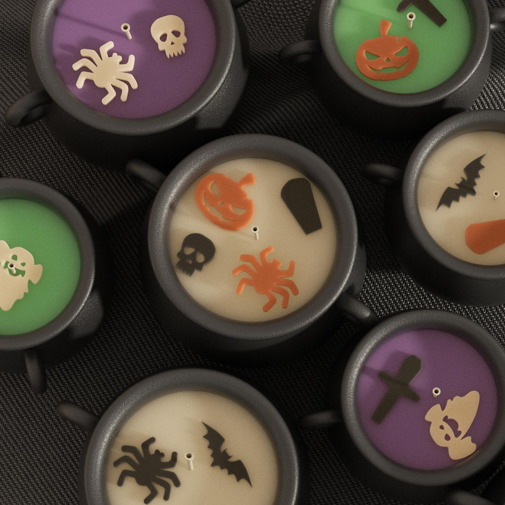 Black cauldron-shaped candles with colorful wax tops decorated with Halloween motifs like spiders, bats, pumpkins, skulls, and coffins - Boowan Nicole