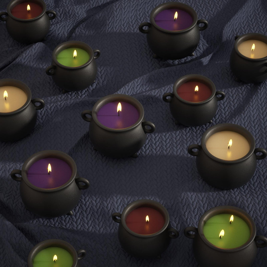 Black cauldron-shaped candles with colorful wax in purple, green, red, and yellow, burning on a dark textured cloth background - Boowan Nicole