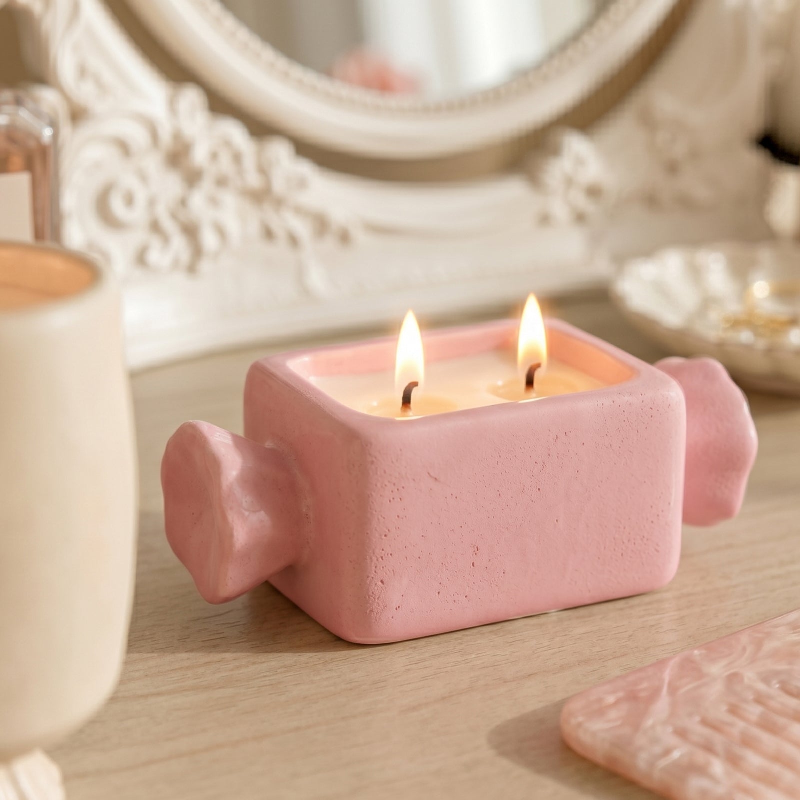 Pink rectangular wrapped bonbon two-wick candle jar with textured matte finish, lit candle flame vanity close-up shot - Boowan Nicole