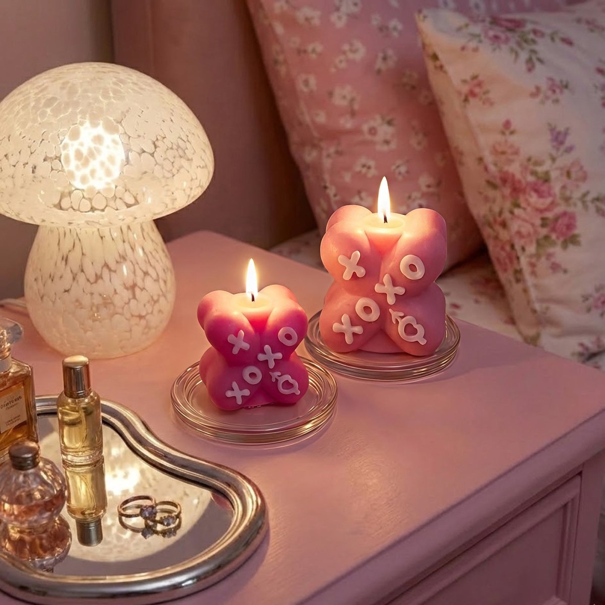 Two lit pink X-shaped XOXO candles on a nightstand with a glass mushroom lamp - Boowan Nicole