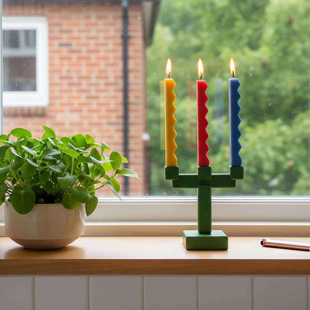 Three zigzag-edge taper candles in a green three-arm holder on a windowsill - Boowan Nicole