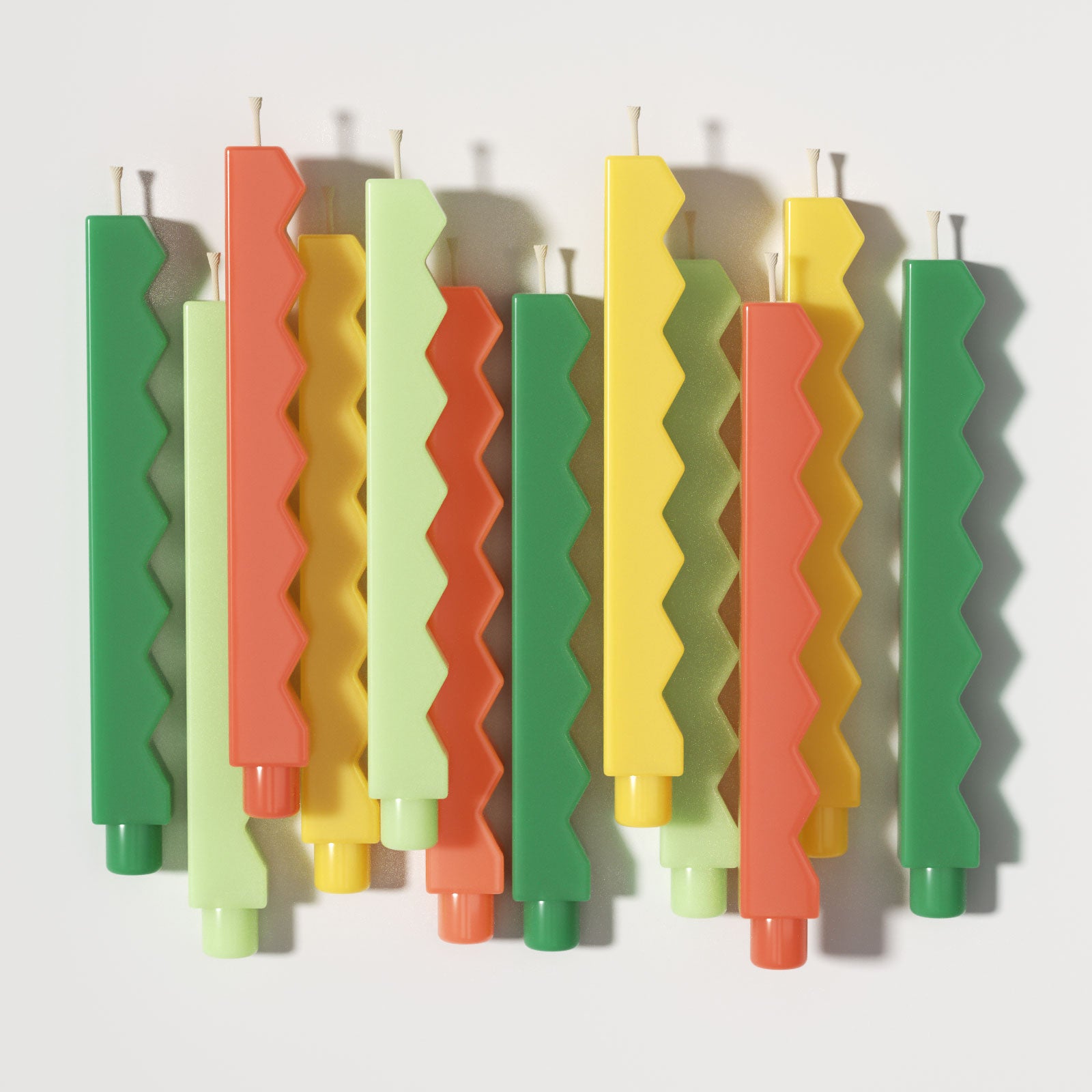 Colorful zigzag-edge taper candles flat lay in green, yellow, and orange tones - Boowan Nicole
