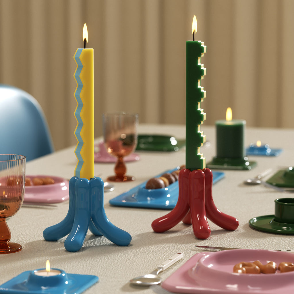 Yellow zigzag-edge and green stair-step taper candles in blue and red holders on a modern dining table - Boowan Nicole