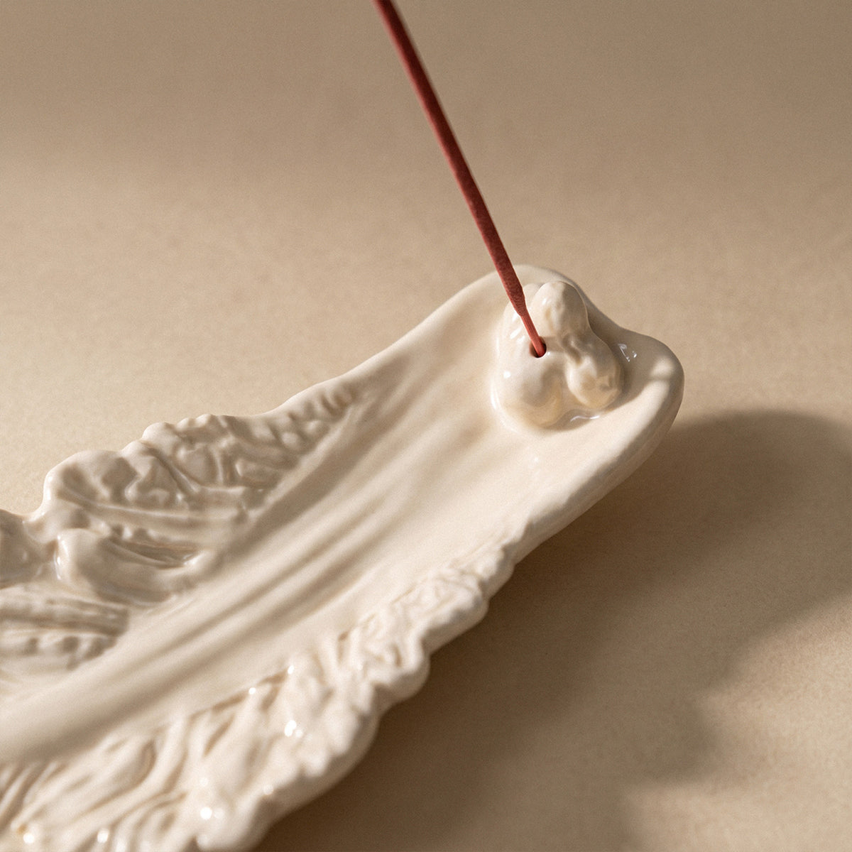 Close-up of sculpted cabbage leaf veins and raised incense-stick support