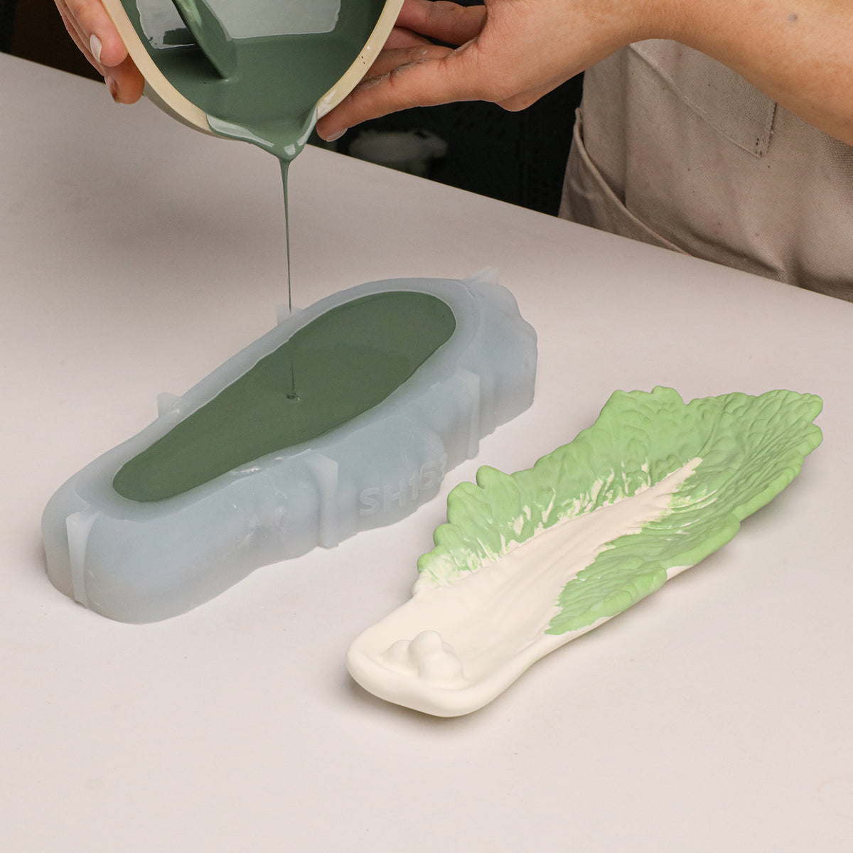 Filled leaf-shaped silicone mold beside a green and cream casting