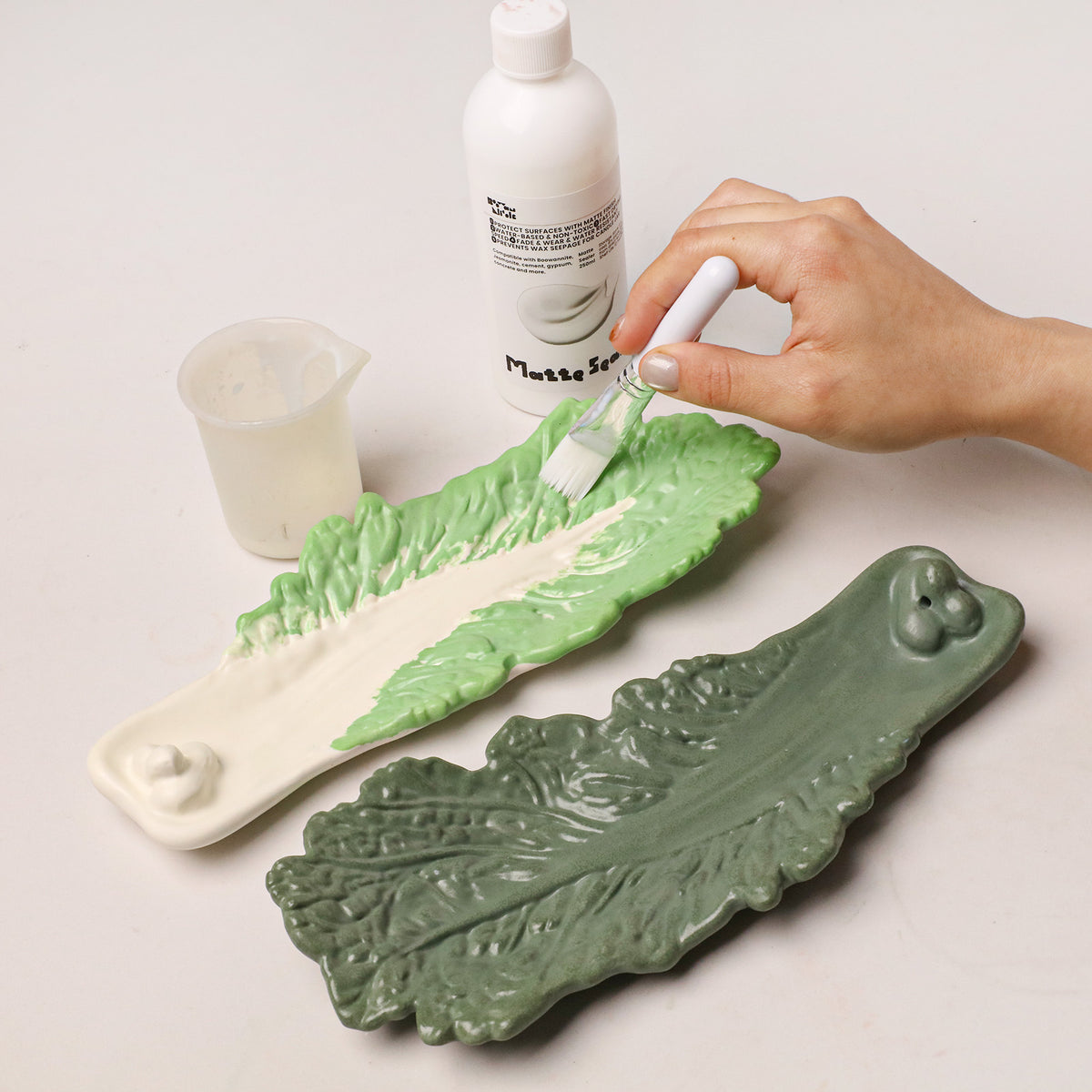 Brushing matte sealer onto a green and cream leaf incense holder