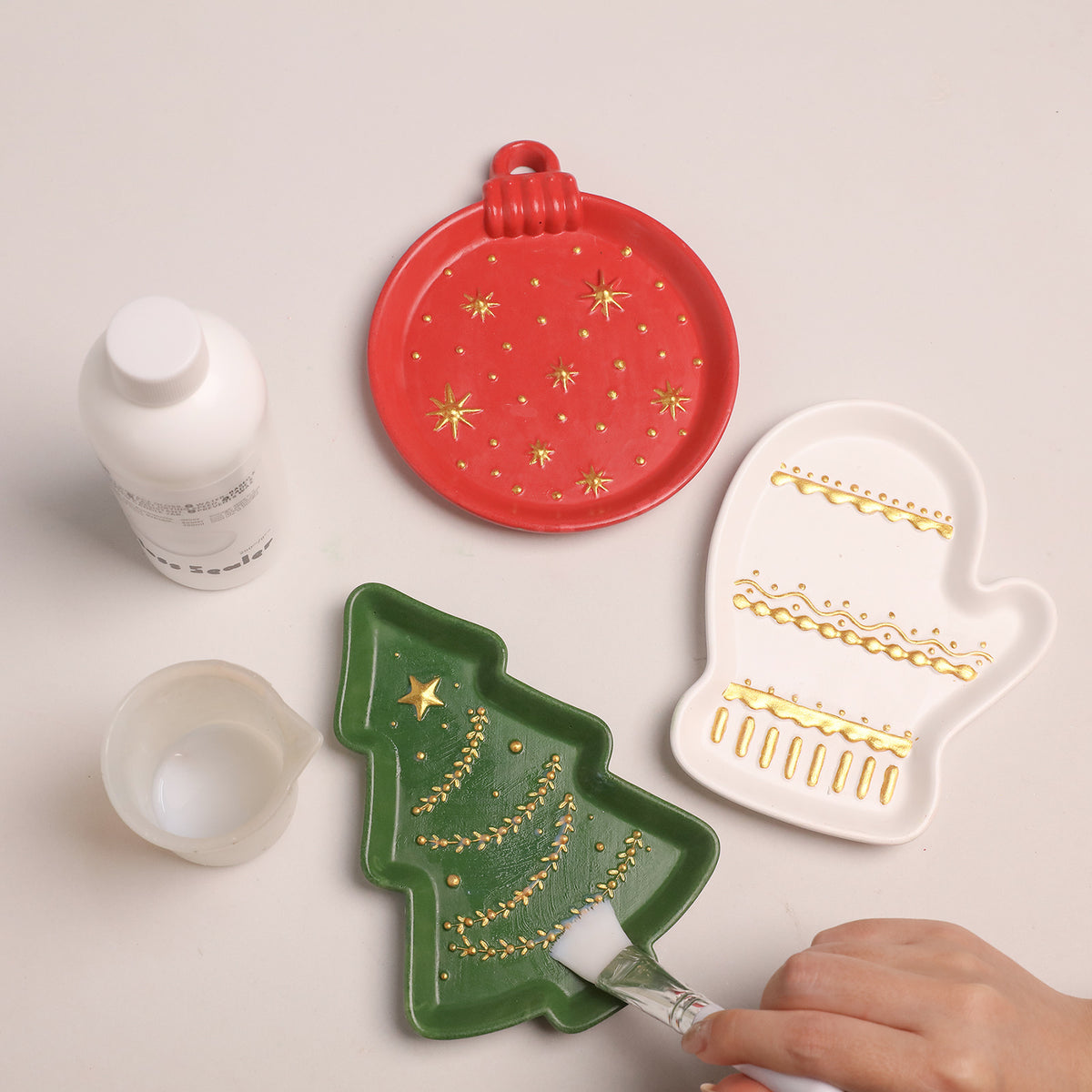 Applying glossy sealer to a green Christmas tree tray with a sponge brush