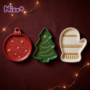 Red ornament, green Christmas tree and cream mitten cement trays with gold painted details on a burgundy holiday tablecloth