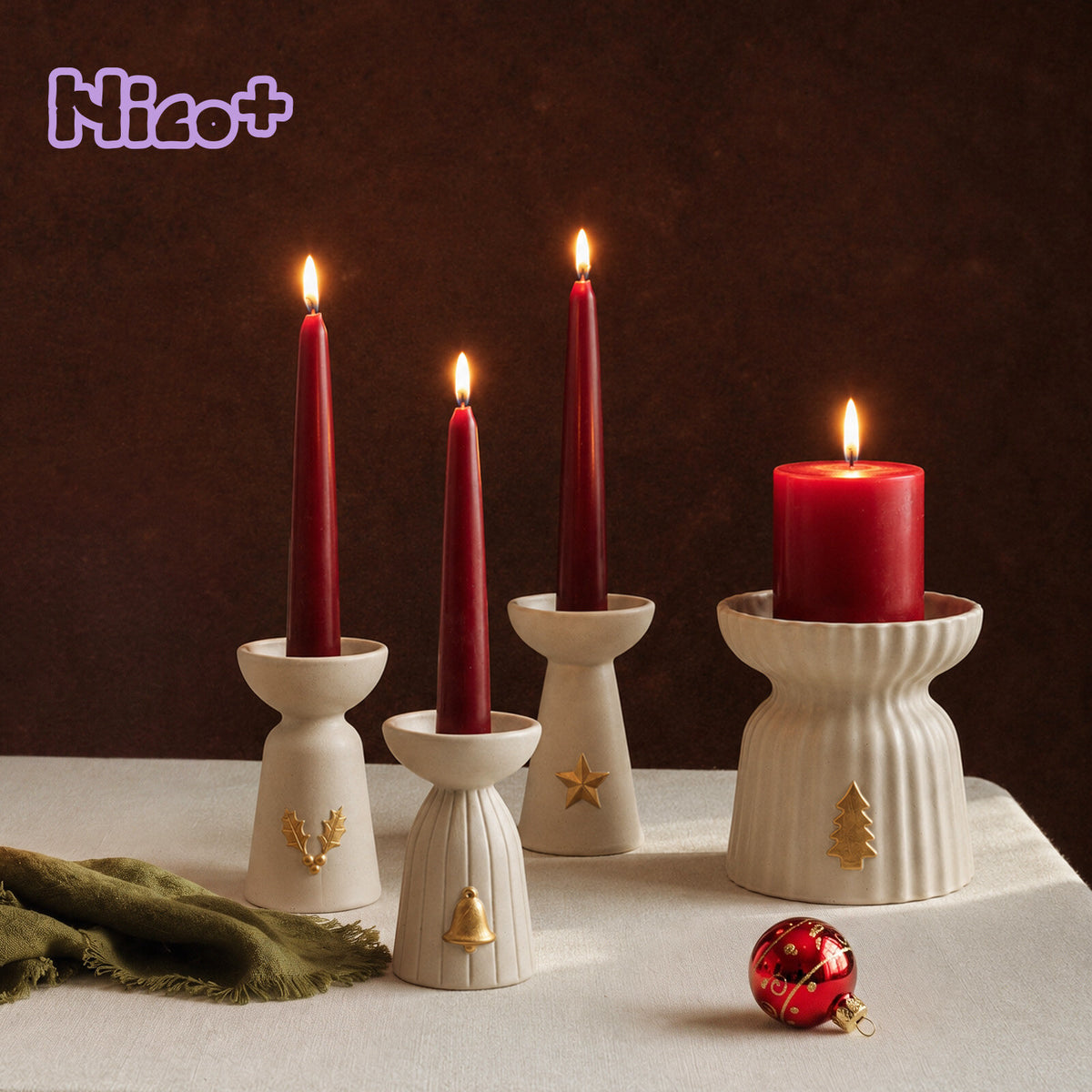 Christmas Glow candle holders with holly, bell, star and tree gold charms holding lit red taper and pillar candles, Nico+ logo