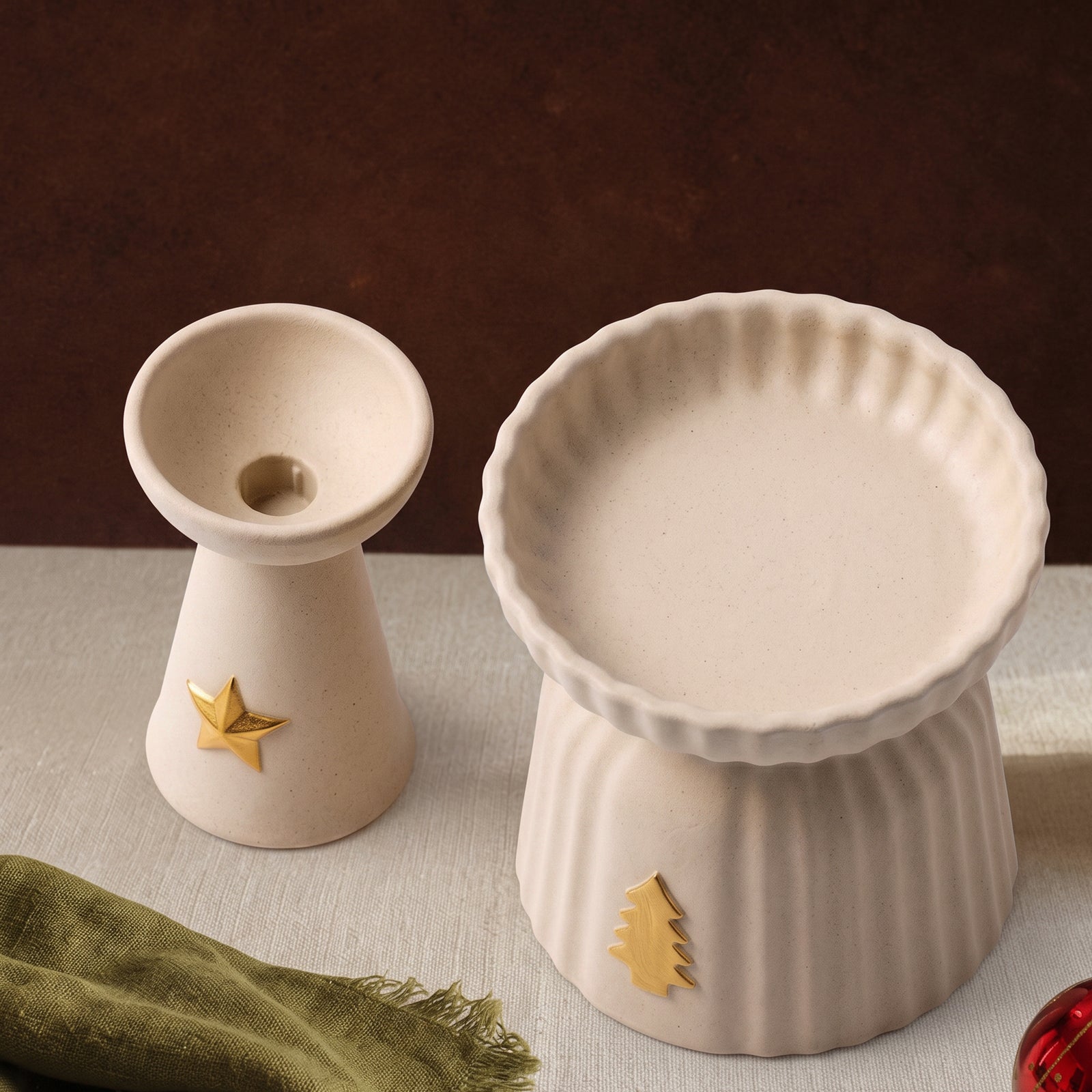 Two empty Christmas Glow candle holders side by side — the star charm taper holder and the larger ribbed pillar holder with a gold tree charm.