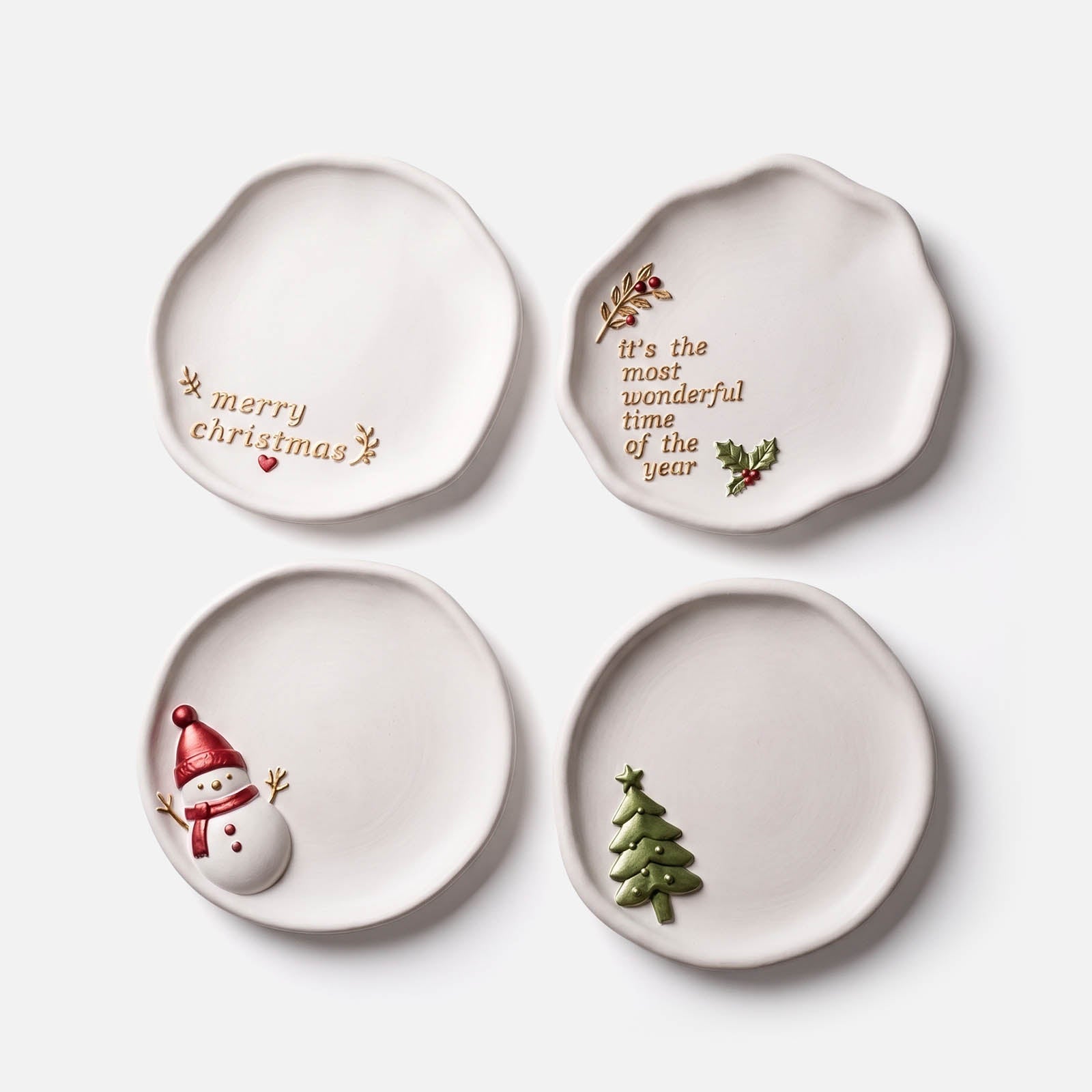 Four organic ceramic-look Christmas trinket trays — snowman, Merry Christmas text, It's the Most Wonderful Time of the Year text, and Christmas tree designs — on a white background.