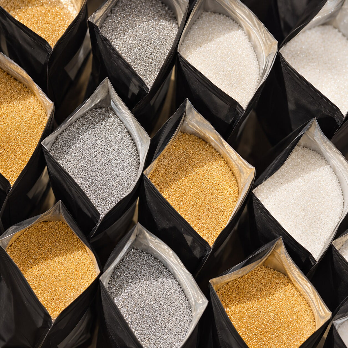 Open bags of gold, silver and white pearl sand wax granules