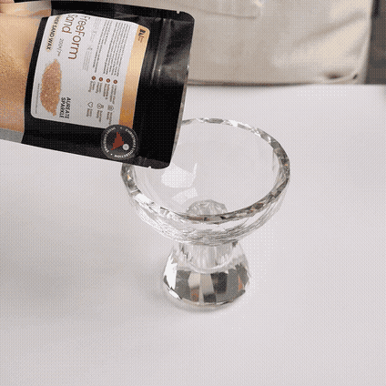 Pouring pearl sand wax from the bag into a crystal glass vessel