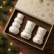 Three white snowman candle jars with gold details in a snowman gift box
